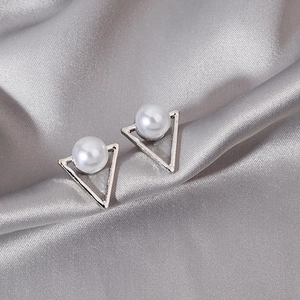 Elegant silver triangle stud earrings with white pearls on a grey silk background