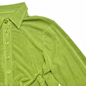 Detail of green ribbed knit fabric showing the lapel collar and matching buttons