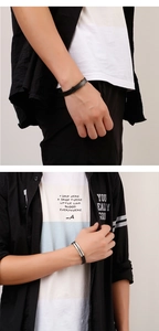 Close-up of minimalist black braided leather bracelet with stainless steel plate on wrist