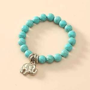 Bohemian turquoise beaded stretch bracelet with vintage silver elephant charm on beige background