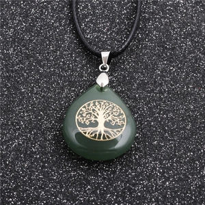 Green teardrop tree of life pendant necklace with black cord on a textured background