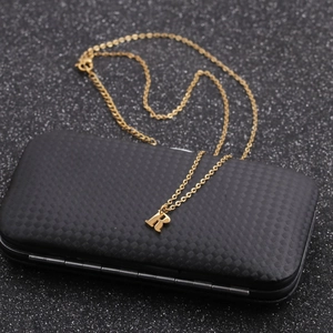 Macro detail of gold stainless steel necklace with letter R pendant on a black box