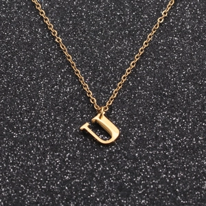 Macro shot of a polished golden stainless steel letter U pendant necklace on black background