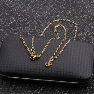 Detailed view of a gold horseshoe necklace chain displayed on a textured black jewelry box