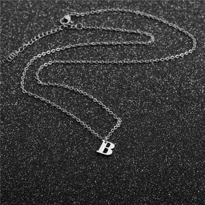 Macro view of minimalist silver stainless steel necklace with letter B pendant detail