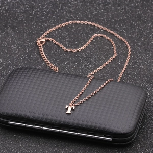 Detailed view of rose gold letter T necklace pendant on black textured jewelry box