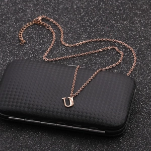Detail of rose gold stainless steel necklace featuring a minimalist U letter pendant