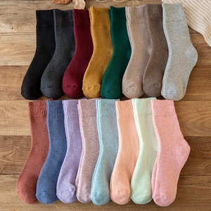 Thick warm wool-blend socks for women in 16 assorted solid colors on a wooden background