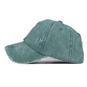 Détail de la casquette en coton lavé montrant le bord effiloché et la broderie latérale