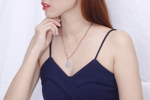 Detail of silver stainless steel coin necklace with embossed portrait on female model