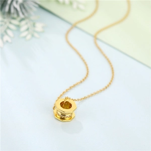 Close-up of gold hexagonal nut pendant with sparkling crystals on a fine chain link