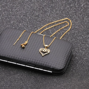 Macro view of gold MOM heart pendant with colorful zircon inlay on premium black texture