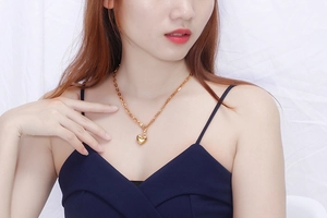 Close-up of a minimalist golden heart pendant necklace worn on a female model