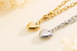 Detail of gold and silver heart pendants on chunky chains over beige background