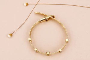 Detail of 18k gold plated mesh band bracelet with square zircon stones and buckle clasp