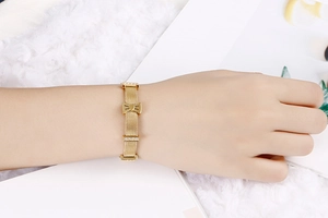 Détail du bracelet en maille dorée avec nœud en strass et texture métallique polie