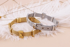 Détail de bracelets en maille avec nœuds en cristal et breloques cœur sur fond doux