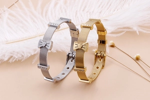 Détails des bracelets en maille dorée et argentée avec nœud et cristaux sur fond doux