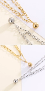 Detail of layered gold and silver necklaces with polished spherical bead pendants