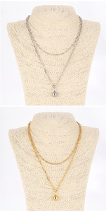 Close-up of double-layer silver and gold necklaces with round ball pendants on a mannequin