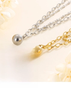 Detailed close-up of polished gold and silver spherical pendants on layered metal chains