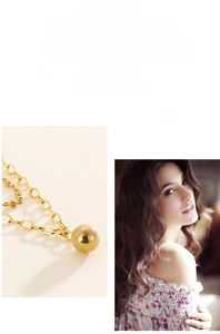 Detail of minimalist 18K gold spherical pendant necklace on a high-fashion model