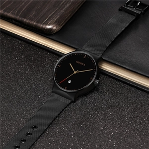 Detail of minimalist black mesh strap watch featuring a date window and gold hands