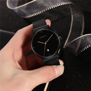 Macro detail of men's black alloy mesh watch featuring a calendar window and gold hands