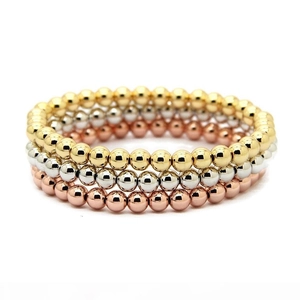Detailed view of three stackable metal bead bracelets in gold, silver, and rose gold finish