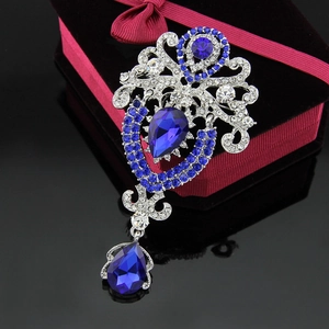 Macro detail of crown brooch with blue teardrop crystals and sparkling rhinestones