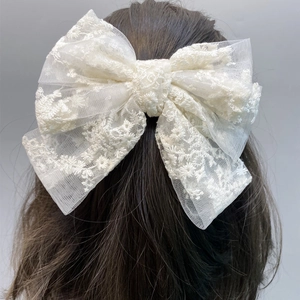 Close-up of white lace double bow hair clip with floral embroidery on long hair