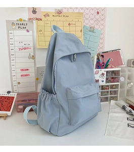 Dettaglio dello zaino in nylon impermeabile azzurro con tasca frontale e tasche laterali