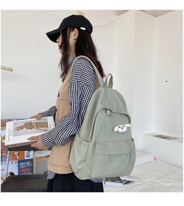 Vista laterale dello zaino grande in nylon verde chiaro impermeabile indossato da studentessa