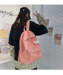 Zaino rosa minimalista impermeabile con ciondolo a pecora per studentesse su una scrivania