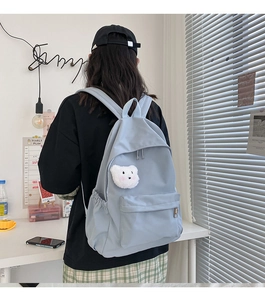 Dettaglio dello zaino in nylon azzurro con un simpatico ciondolo a forma di orsetto di peluche