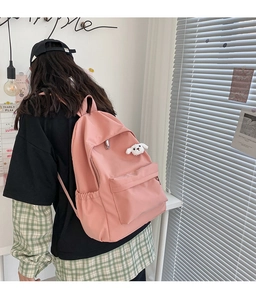 Zaino in nylon rosa con ciondolo a forma di cucciolo bianco in un interno luminoso