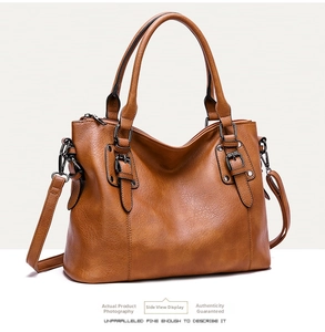 Detailed side view of brown tote bag showing textured leather and bronze metal buckles