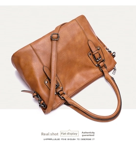 Detail of vintage brown leather handbag with adjustable strap and textured surface