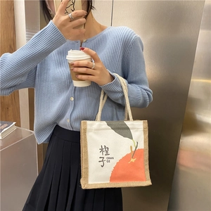 Detail of canvas tote bag with orange print, jute splicing and thick rope handles