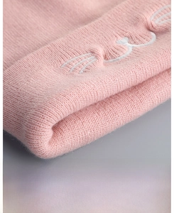 Detail of pink knit hat with soft wool texture and cute embroidered cat whiskers