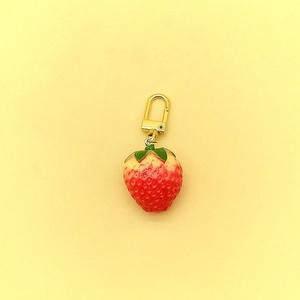 Close-up of a realistic red strawberry keychain with green leaves and golden metal clasp