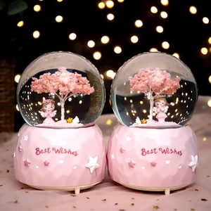 Pink cherry blossom snow globe music box with a girl figurine and warm lighting