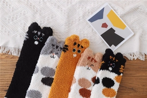 Detailed view of five pairs of fluffy coral fleece cat socks with 3D ears on wooden surface