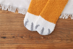 Close-up of fluffy orange and white coral fleece socks with cute cat paw pad detail