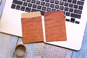 Close-up of wood grain patterned brown paper envelopes on a laptop keyboard workspace