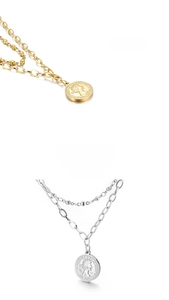 Detail of layered gold and silver coin necklaces featuring embossed queen portrait charms