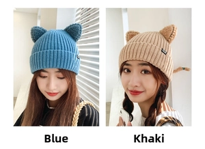 Close-up of cute cat ears and small fabric labels on knitted winter beanies in blue and khaki