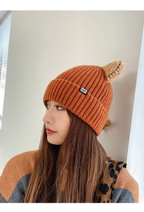 Detail of orange knitted beanie with brown cat ears and small black CAT logo tag