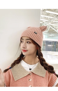 Detail of pink knitted beanie with cute cat ears and a small black woven tag