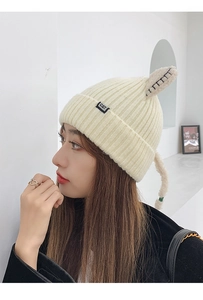 Close-up of beige knitted hat featuring cute cat ears and a small CAT brand label